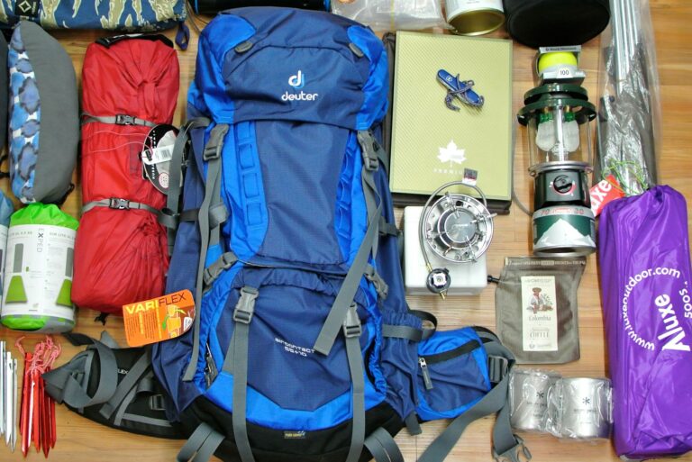 72-hour bug-out bag gear layout showing a backpack, sleeping bags, camping stove, lantern, cookware, and emergency supplies arranged for a survival kit checklist.