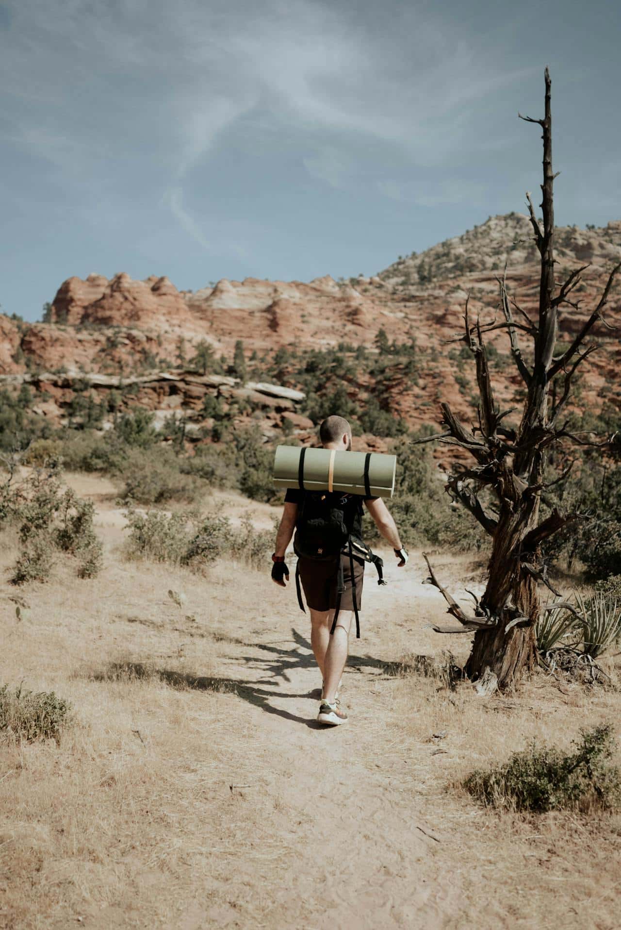 backpacker carrying survival gear hiking through desert terrain during a desert survival journey