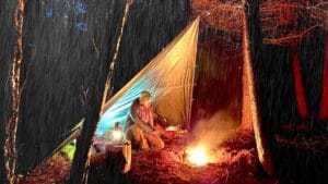 Campfire burning under a tarp in the rain during a woodland camping trip
