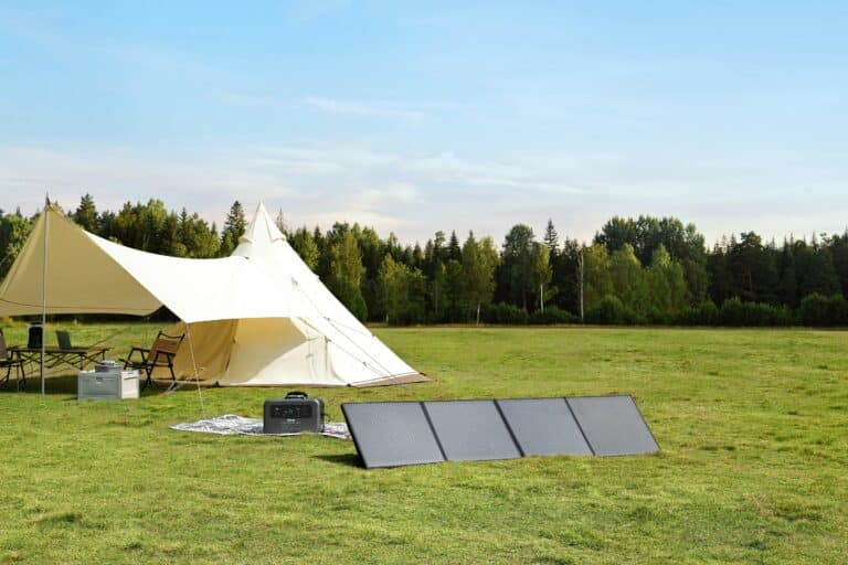 Large canvas tent set up on grassy field with portable solar panels and a generator in front, clear sky and forest in the background.