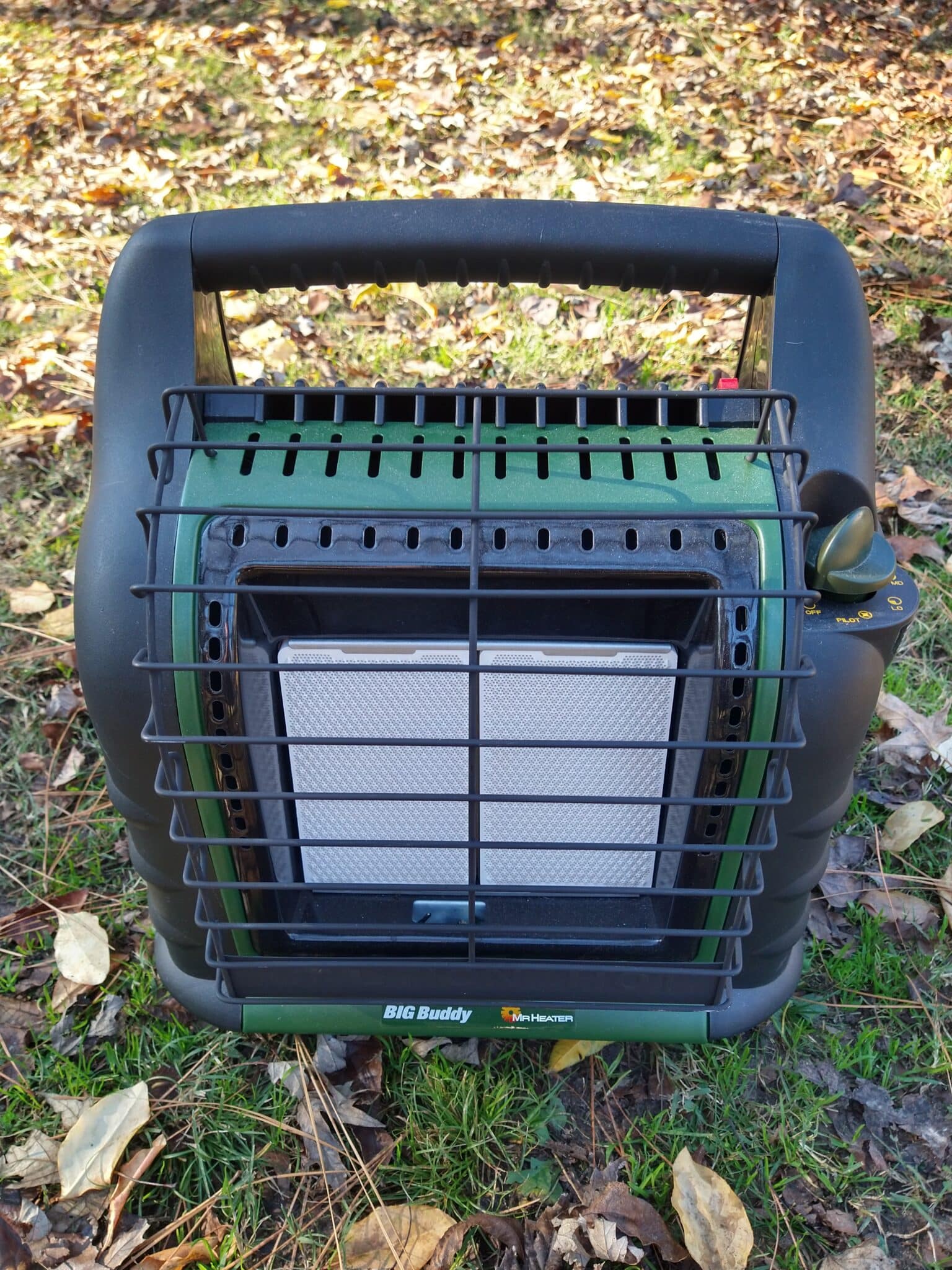 Indoor-safe Mr. Heater Big Buddy propane heater sitting on grass outdoors — reliable portable emergency heater for power outages and winter survival.