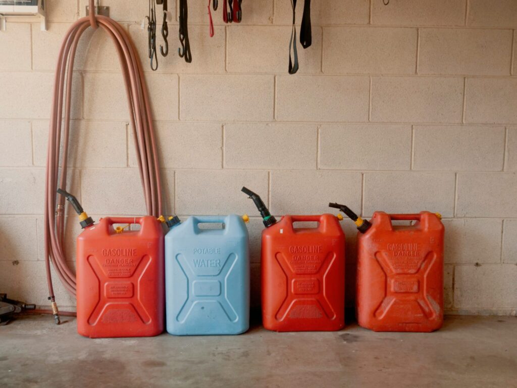 Organized gasoline storage cans lined up safely inside a garage for emergency fuel preparedness and long-term storage.