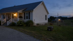 Portable generator powering a well-maintained rural homestead and barn during an evening blackout.